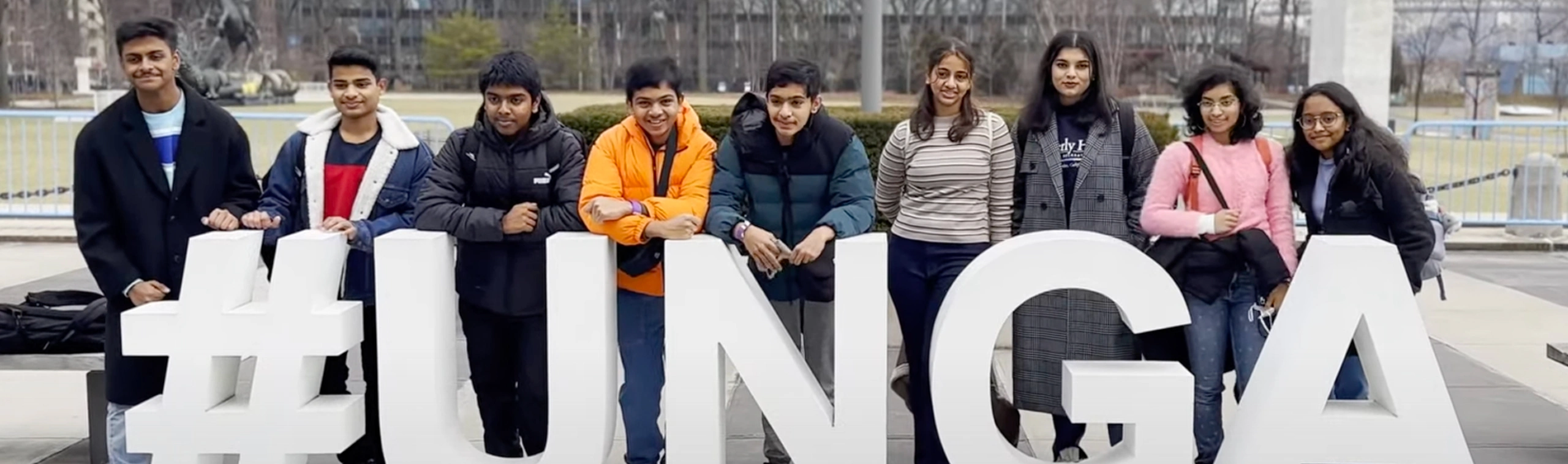 Group of students pose with large hashtag UNGA sign, smiling outdoors.