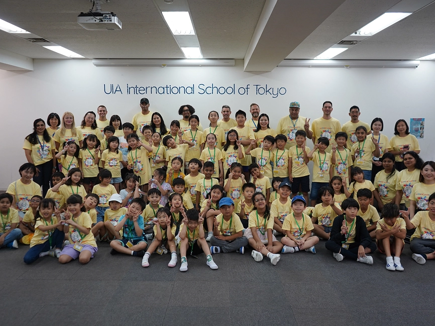 Group photo of students and teachers in yellow shirts at UIA International School of Tokyo.