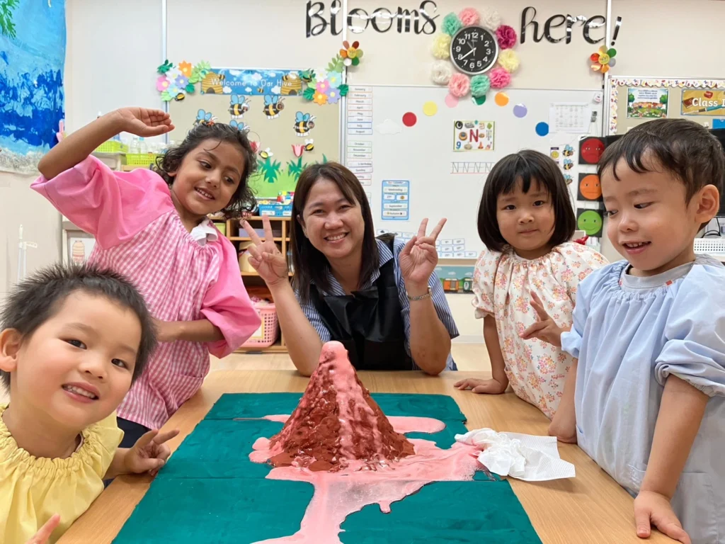 Teacher and kids enjoy a volcano science project in a colorful classroom setting.