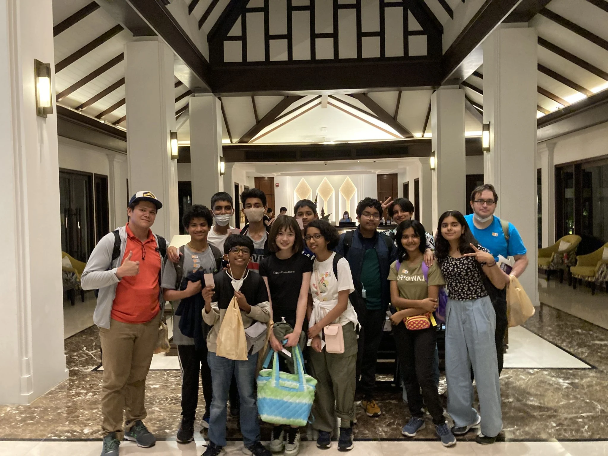 Group of people posing together in a hotel lobby, showcasing a diverse and cheerful gathering.