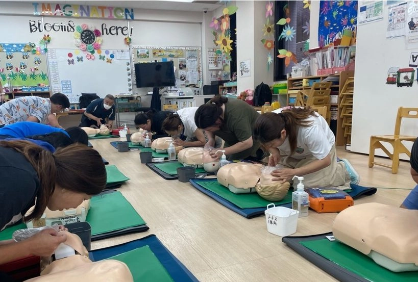 People practice CPR techniques on mannequins in a classroom setting during a training session.