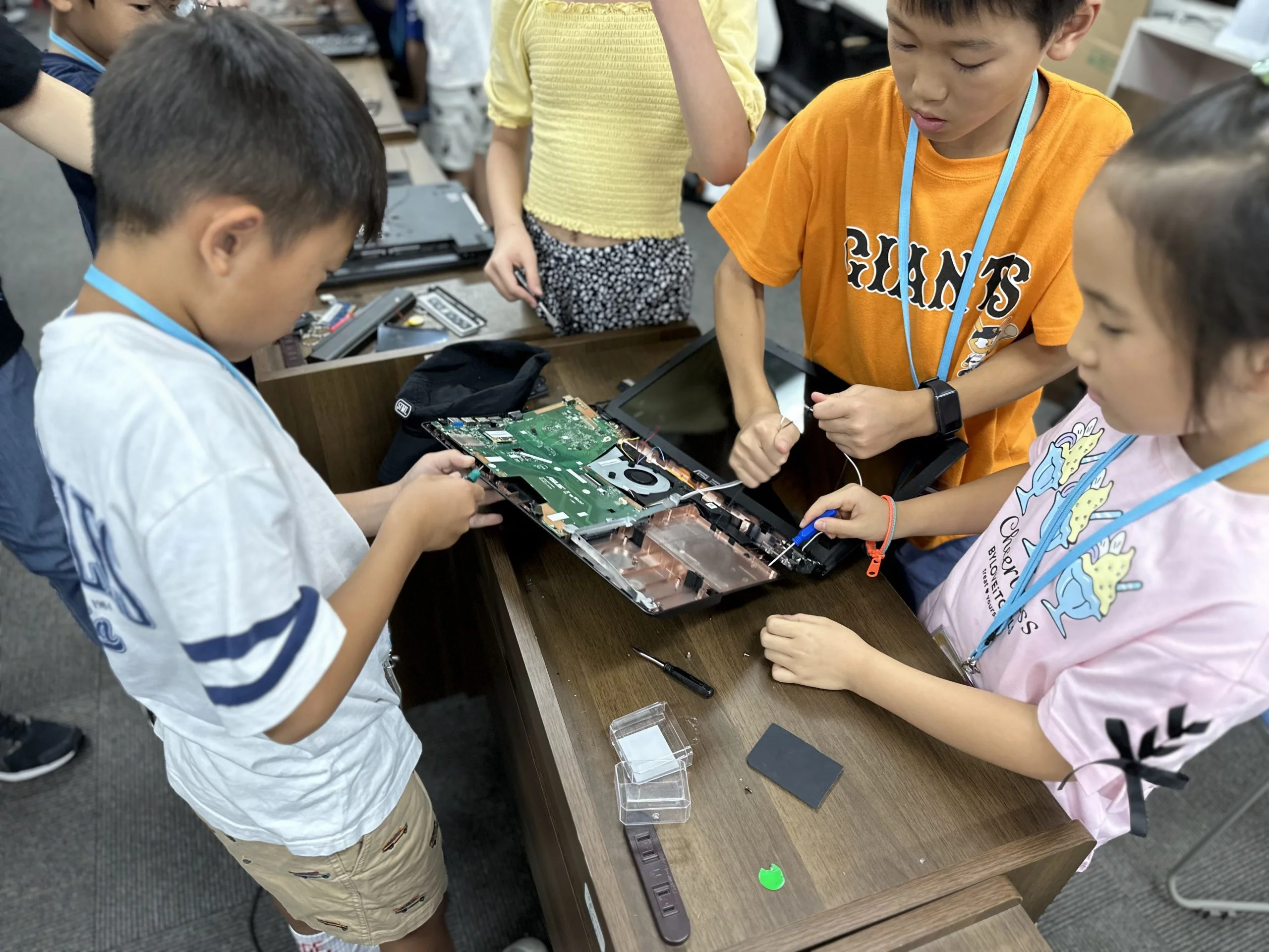 Children collaborating on a computer project, exploring hardware components at a tech workshop.