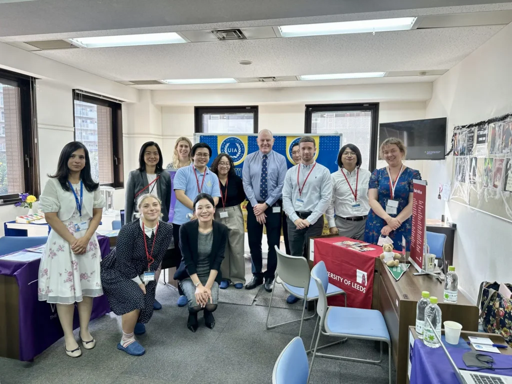 Group of professionals at a conference event, smiling for a group photo indoors, with University of Leeds materials.