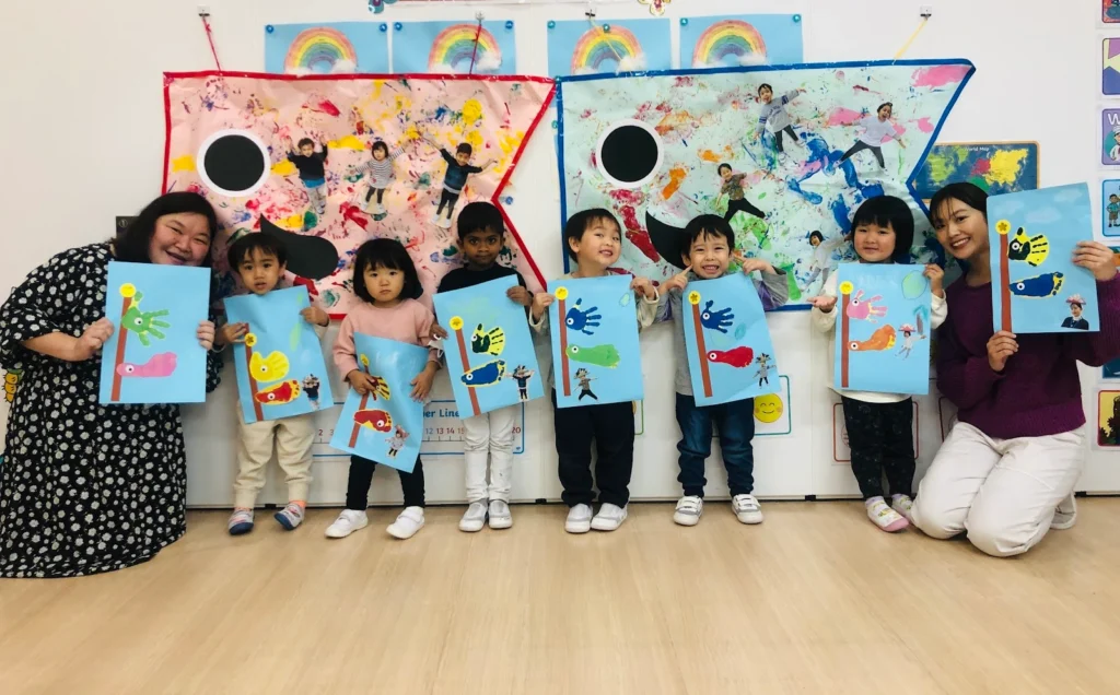 Children and teachers displaying vibrant handprint art in a classroom setting, colorful backgrounds with rainbows.