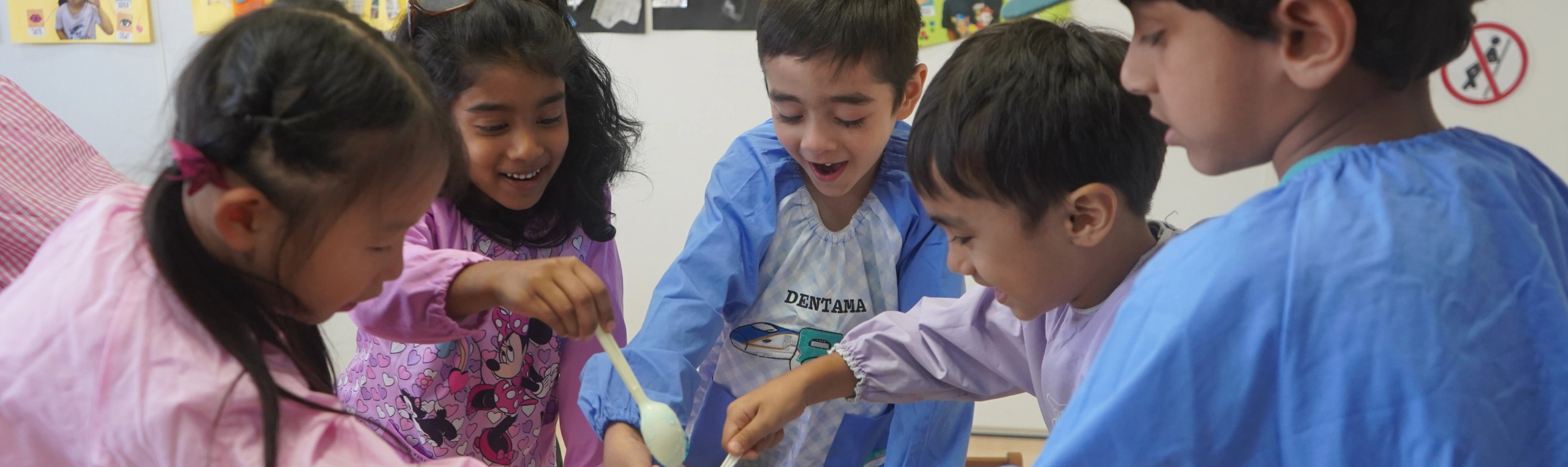 Children engaged in a creative activity at school, smiling and working together in a classroom setting.