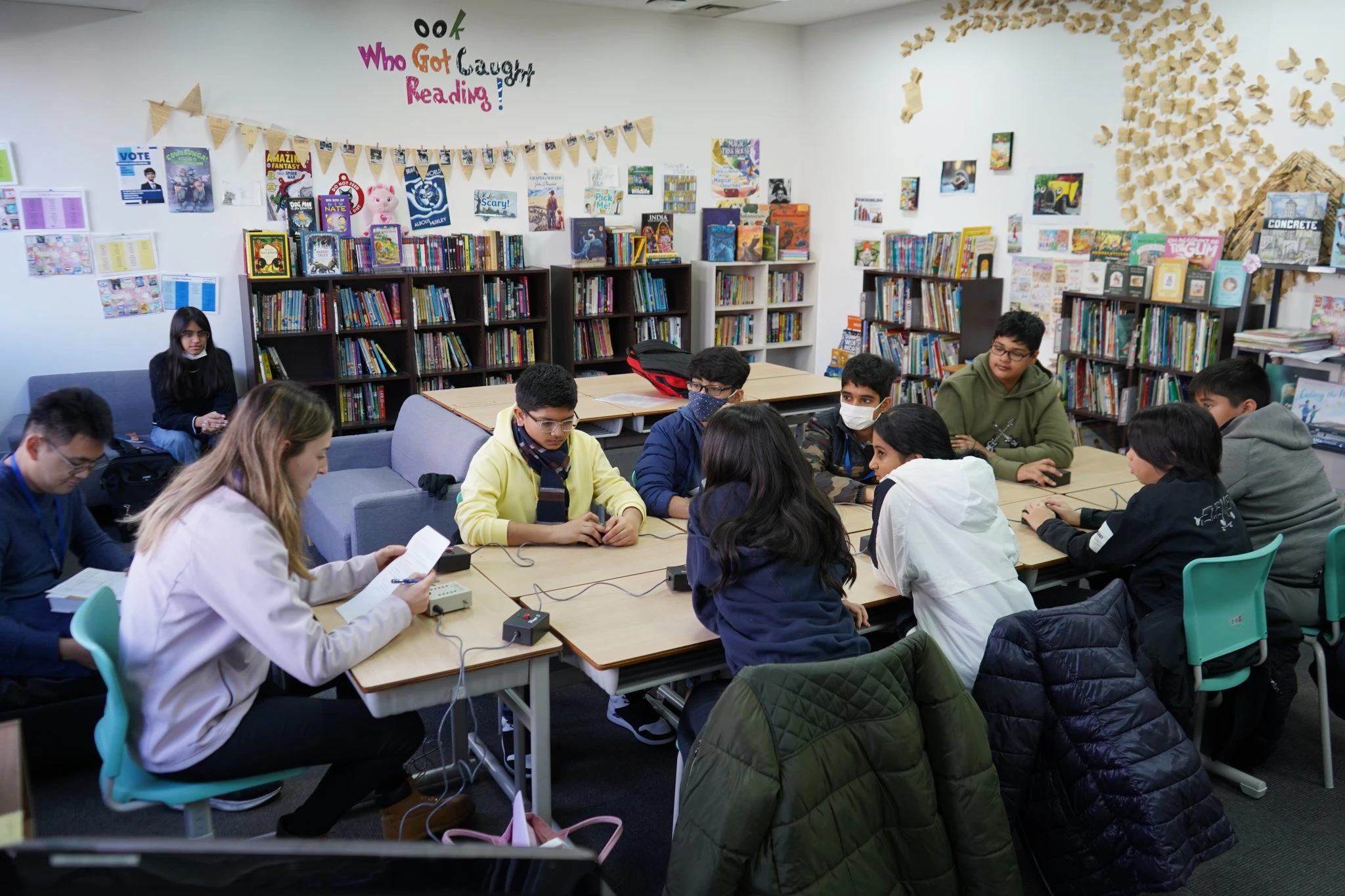 Students collaborating in a library, engaging in a group activity with books and notes around them.
