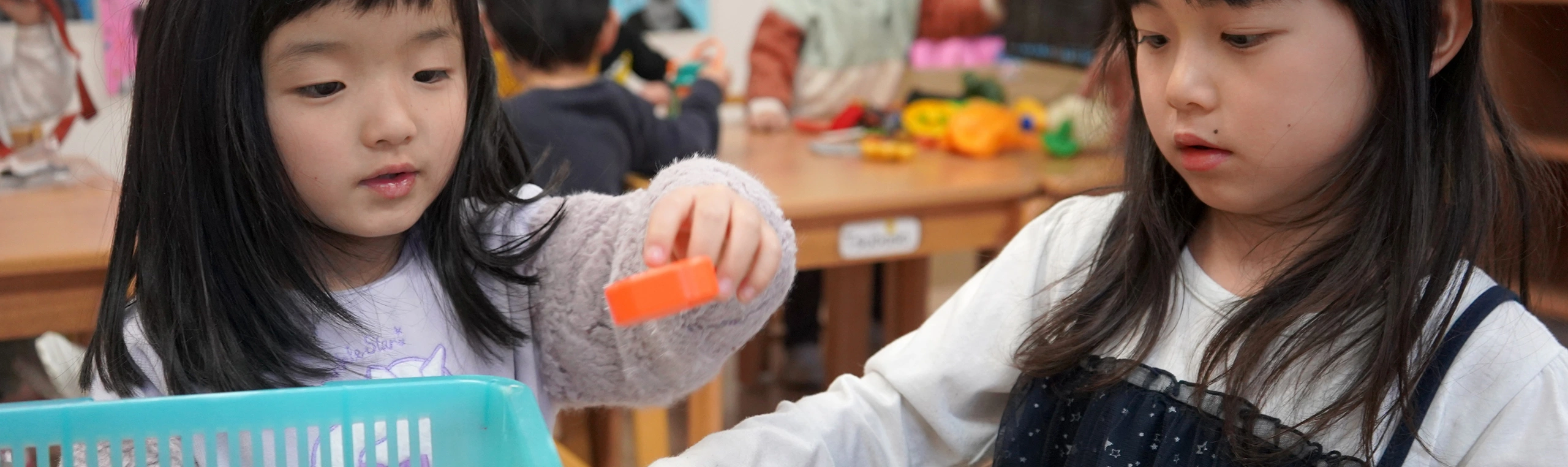 Two children playing with colorful blocks at a classroom table, engaging in a fun educational activity.