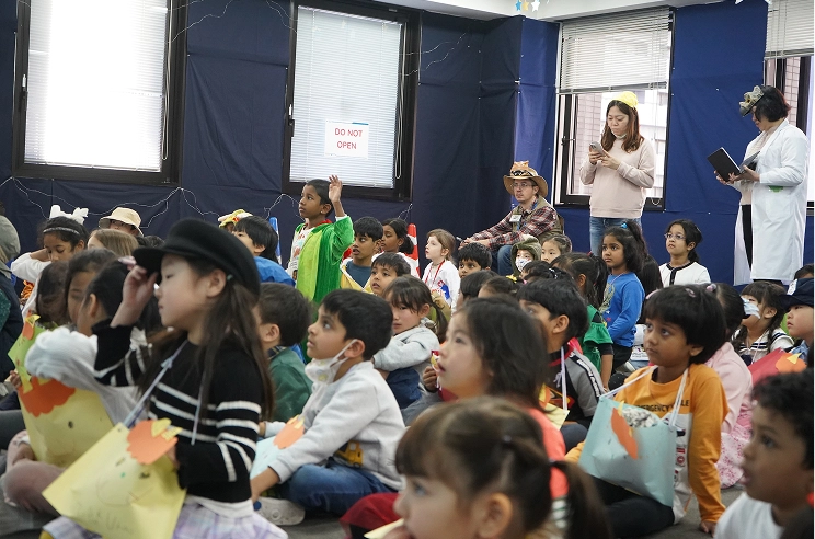 Children in costumes sitting attentively in a classroom, engaged in a lively group activity.