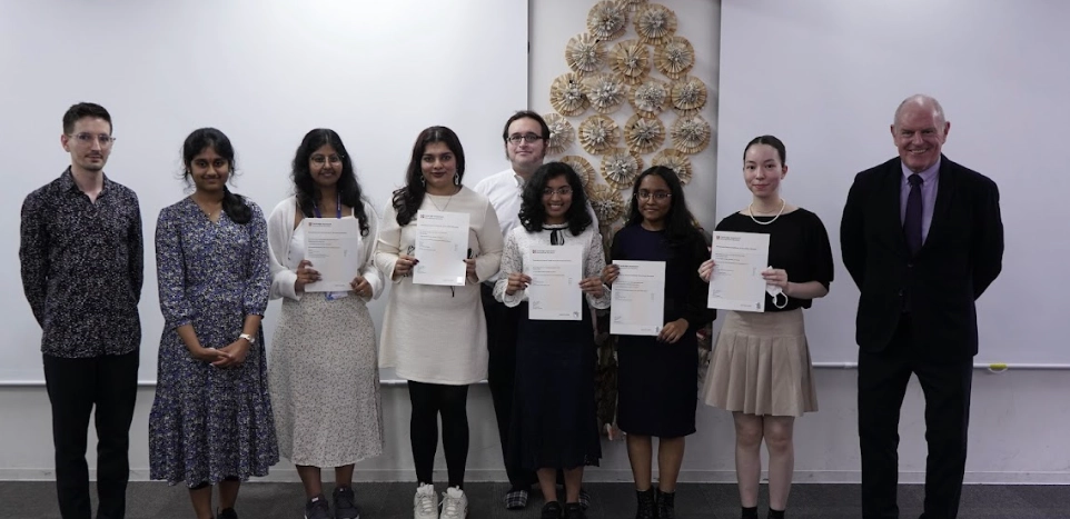 Group of people proudly holding certificates in a room, celebrating an achievement together.