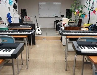 Music classroom with keyboards, guitar, and stage setup for lessons or practice. Bright and creative learning environment.