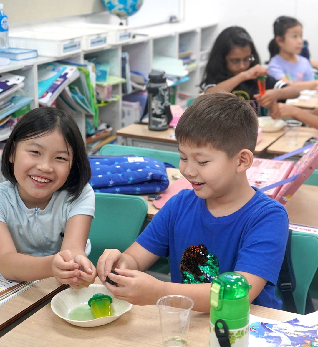Children engaged in a fun science experiment at school, smiling and learning hands-on at their classroom desk.